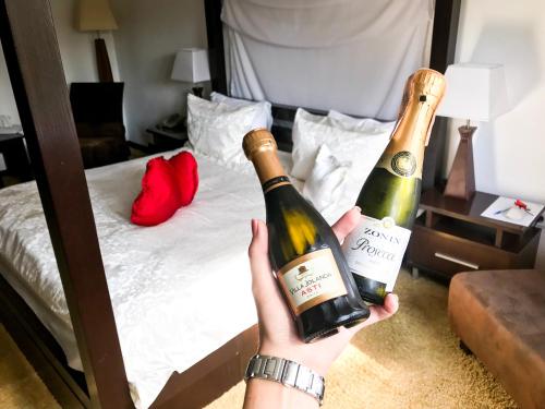 a person holding two bottles of wine in front of a bed at SPA Hotel in Vorzelʼ