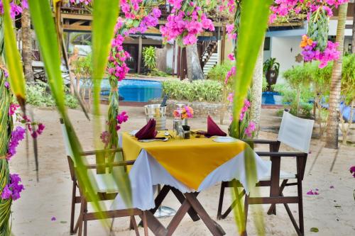 a table and chairs with a yellow table and pink flowers at Kena Beach Hotel in Matemwe