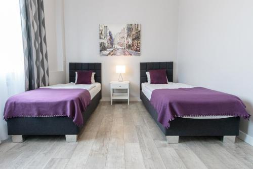 Habitación con 2 camas con colchas de color púrpura y suelo de madera. en Rental Apartments Krochmalna en Varsovia