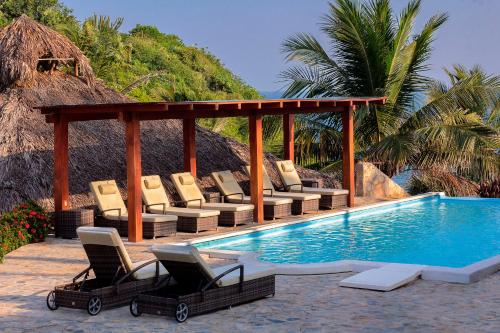 un gruppo di sedie a sdraio accanto alla piscina di Villas & Resort Luz de Luna a Santa Cruz Huatulco