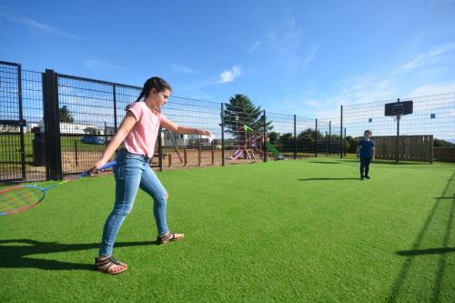 a young girl swinging a tennis racket on a field at Causeway Coast Apartment in Ballycastle