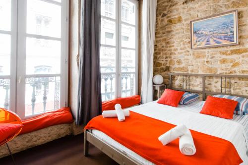 a bedroom with two beds with orange and white pillows at Constantine Terreaux in Lyon