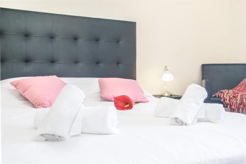 uma grande cama branca com almofadas cor-de-rosa e brancas em Arcadas Cozy Apartments - AV no Funchal