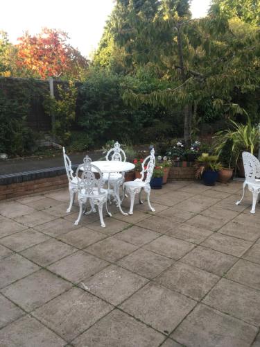 four white chairs and a table in a garden at Elmdon Lodge in Birmingham