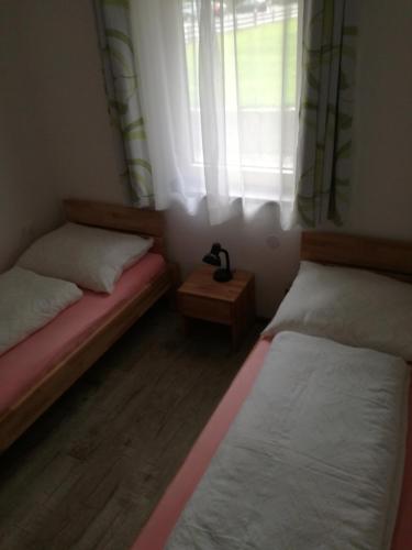 アウフファッハにあるKapellhäuslのベッド2台と窓が備わる小さな客室です。