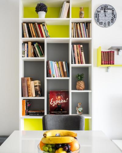 a table with a bowl of fruit in front of a book shelf at Apartman Biblioteka Čardaka 10/61 in Kopaonik