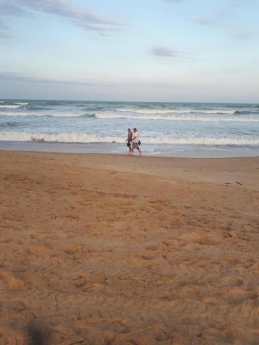 dos personas caminando por la playa cerca del océano en Casa em Unamar,Cabo Frio,à 200m da praia,em condomínio com segurança 24 hs, en Cabo Frío