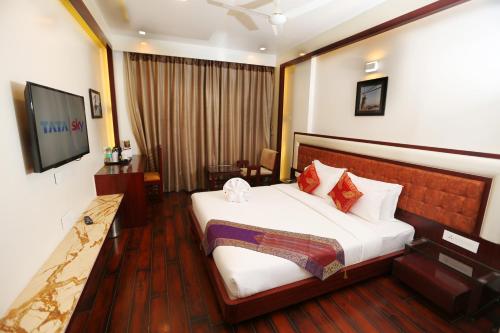 a hotel room with a bed and a flat screen tv at Comfort Inn Benares in Varanasi
