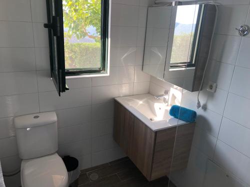 a bathroom with a toilet and a sink and a window at Luxus Tholos Bay in Thólos