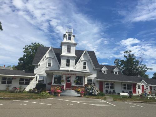 a white house with a tower on top of it at Lakelawn B&B and Motel in Yarmouth