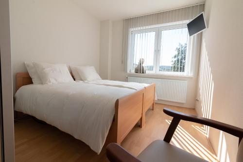 a white bedroom with a bed and a window at Appartement Schin op Geul in Schin op Geul