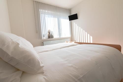 a white bed in a white bedroom with a window at Appartement Schin op Geul in Schin op Geul