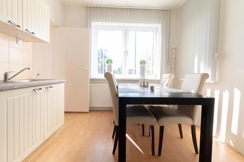 a kitchen with a black table and white chairs at Appartement Schin op Geul in Schin op Geul
