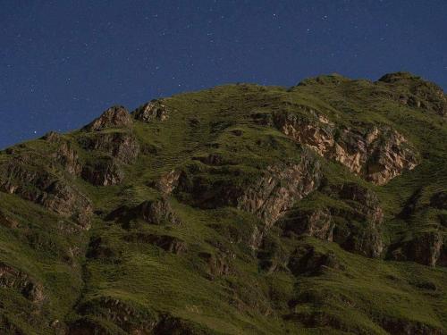 a mountain covered in green grass at night at Wayqi Wasi in Pisac