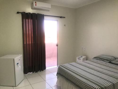 a bedroom with a bed and a sliding glass door at Pousada Aerogrill in Juazeiro do Norte