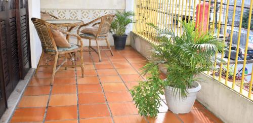 a balcony with chairs and a table and plants at Sos Hostel in Camaçari