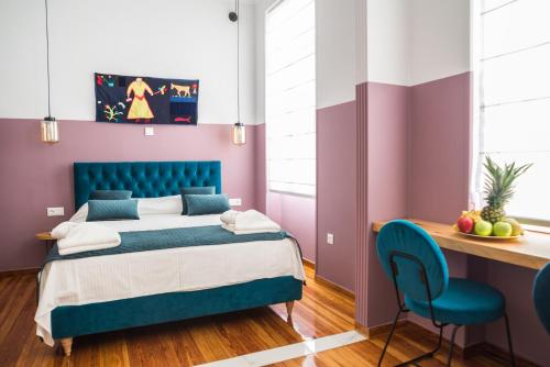 Schlafzimmer mit einem blauen Bett und einem Schreibtisch in der Unterkunft Neratzia Rooms in Athen