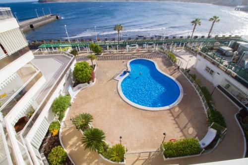 een uitzicht over een zwembad met het strand bij MEDANO4YOU The Harbour Holiday Home in El Médano