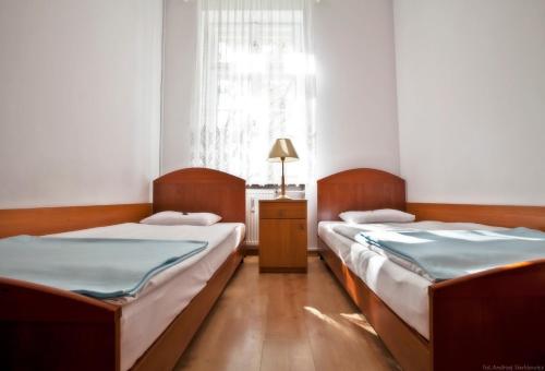 2 łóżka w małym pokoju z oknem w obiekcie DS Cztery Pory Roku w Gdańsku