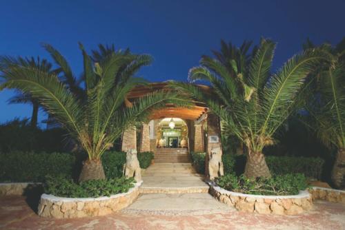 une maison avec deux palmiers et une passerelle dans l'établissement Cupola Bianca Resort, à Lampedusa