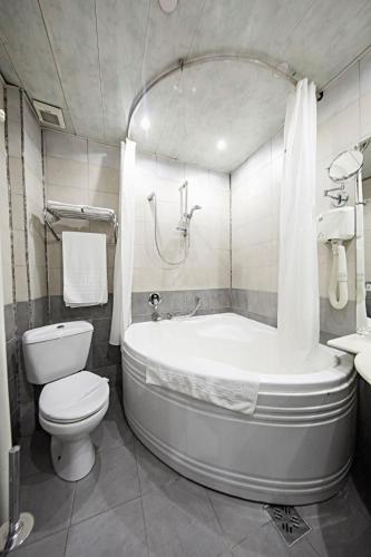 a bathroom with a tub and a toilet and a sink at Relax Comfort Suites Hotel in Bucharest