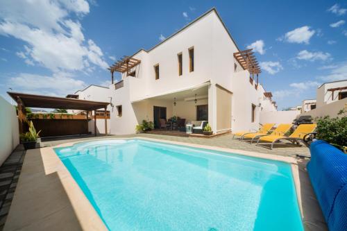 a swimming pool in front of a house at Aquavilla in Costa Teguise