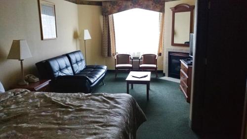a hotel room with a bed and a couch and a chair at Palace Inn & Suites in Lincoln City