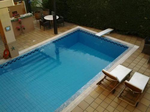 a large swimming pool with two chairs and a table at 4-seasons pool villa near Meteora in Tríkala