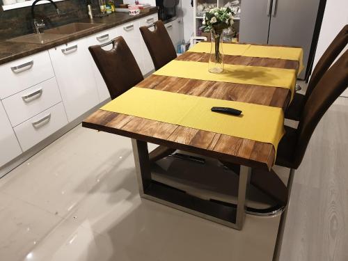 a wooden table with a yellow napkin on it in a kitchen at VillaGrey Tunari in Tunari