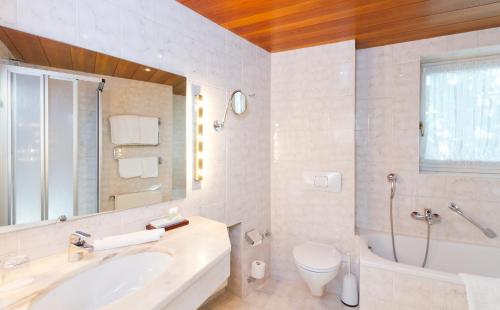 ein Badezimmer mit einem Waschbecken, einer Badewanne und einem WC in der Unterkunft Wittelsbacher Hof Swiss Quality Hotel in Garmisch-Partenkirchen