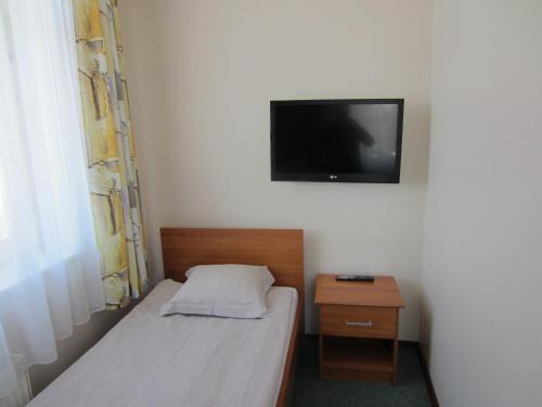 a small bedroom with a bed and a tv on the wall at Livonija in Sigulda