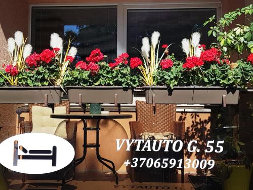 una mesa y sillas frente a una ventana con flores en 2 kambarių apartamentai su virtuve, Trakų miesto centre, en Trakai