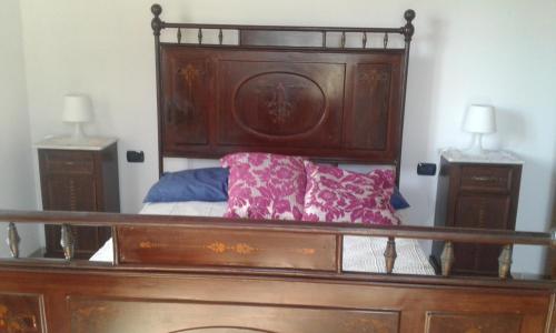 a bed with a wooden headboard and two night stands at CA' MENEGHETTI in Massaciuccoli