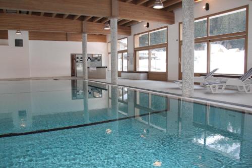 a swimming pool with blue water in a building at Epicéa Lodge Hôtel in Pralognan-la-Vanoise