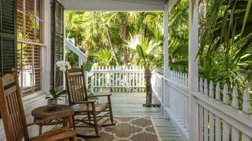 a porch with two rocking chairs and palm trees at Old Town Manor in Key West