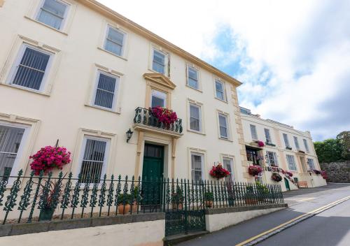 a white house with flowers on the windows and a fence at Pandora Hotel in St Peter Port