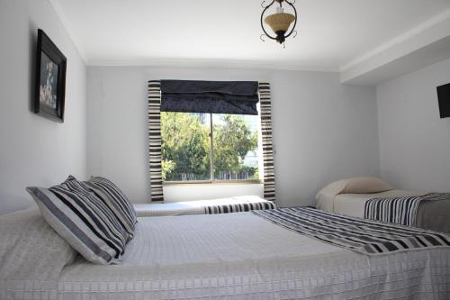 a bedroom with a large bed and a window at Hotel Maquehue in Concepción