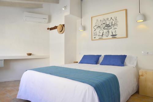 a bedroom with a large white bed with blue pillows at Ca Sa Tieta in Alaró