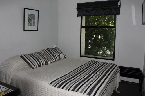 a bedroom with a bed with a striped pillow and a window at Hotel Maquehue in Concepción
