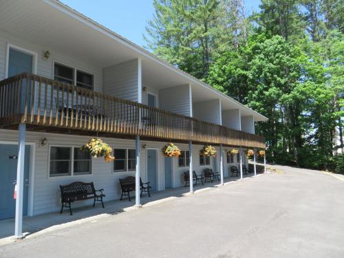 a large white building with a balcony and benches at Bayside Inn & Marina in Cooperstown