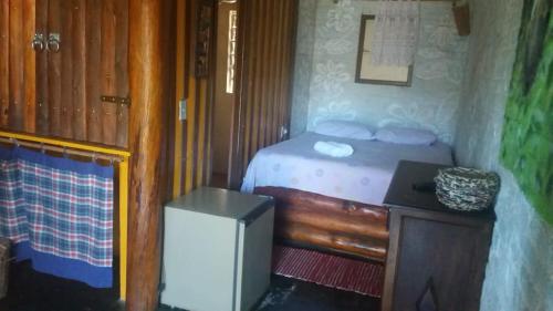 a small bedroom with a bed and a table at A Casinha Pequenina in Monte Verde