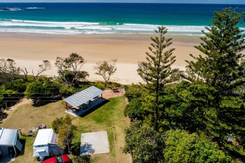 an aerial view of a house and the beach at Woolgoolga Lakeside Holiday Park in Woolgoolga