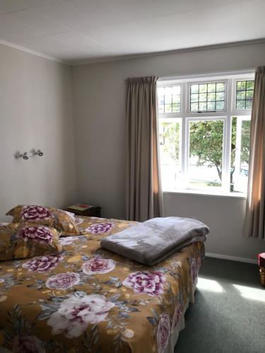a bedroom with a bed with a floral bedspread and a window at Picton House B&B and Motel in Picton