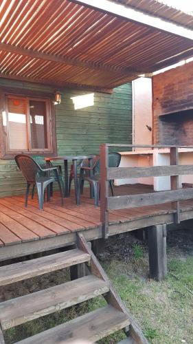 a wooden deck with chairs and tables on a house at Complejo La Pausa in Punta Del Diablo