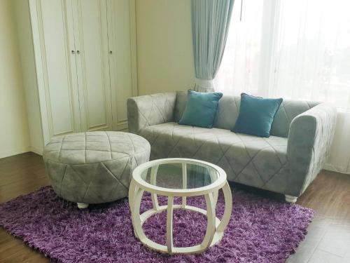 a living room with a couch and a ottoman at The Beverly Hills Hotel in Nakhon Ratchasima