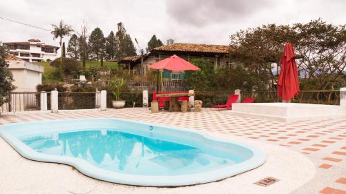 a pool in a yard with a table and a red umbrella at Finca Campestre La Adelita B&B in Salento