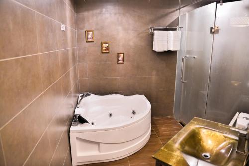 a bathroom with a bath tub and a sink at Shervinton Executive Boutique Hotel in Tawau