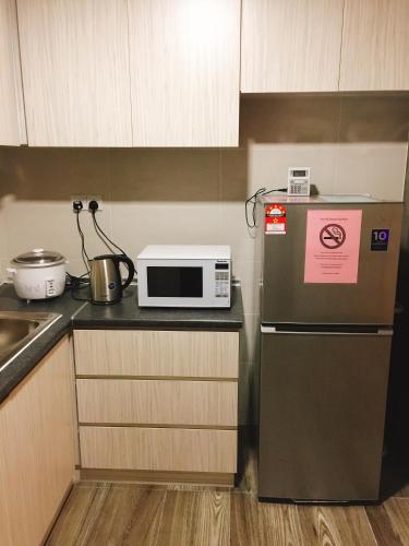 a kitchen with a refrigerator and a microwave on a counter at Perfect Getaway @Vivacity in Kuching