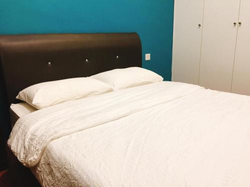 a white bed with a brown headboard and white pillows at Perfect Getaway @Vivacity in Kuching