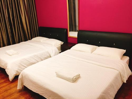 two beds in a hotel room with pink walls at Perfect Getaway @Vivacity in Kuching